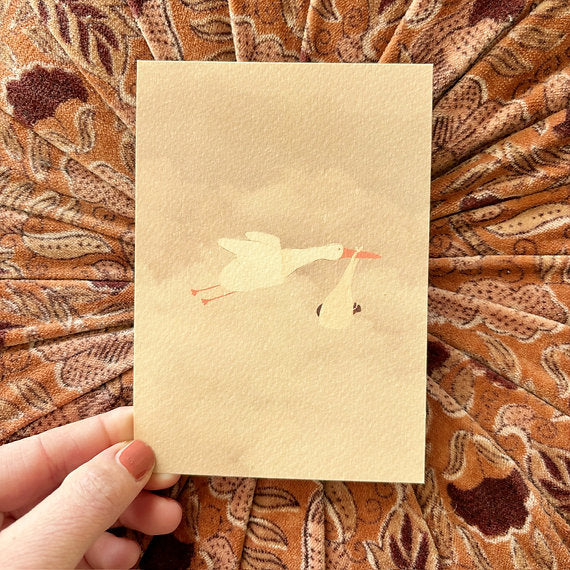 Ansichtkaart met een ooievaar en babydoekje, ontworpen door Lievigheidje en geleverd inclusief kraft envelop.