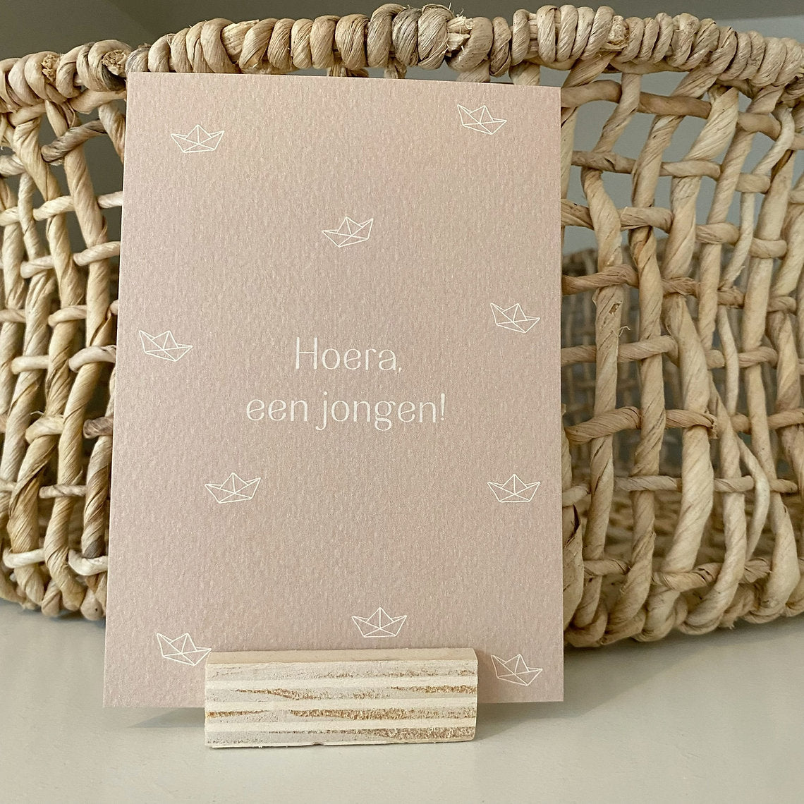 Beige ansichtkaart voor de geboorte van een jongen met tekst Hoera, een jongen! en witte bootjes.