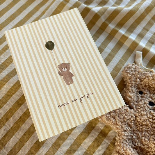Beige gestreepte ansichtkaart voor de geboorte van een jongen met beertje, ballon en tekst Hoera, een jongen.