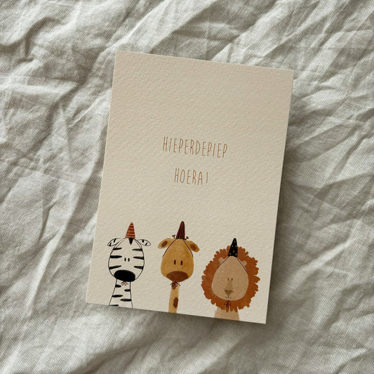 Ansichtkaart voor een verjaardag met zebra, giraffe en leeuw met feesthoedjes en tekst Hieperdepiep hoera.