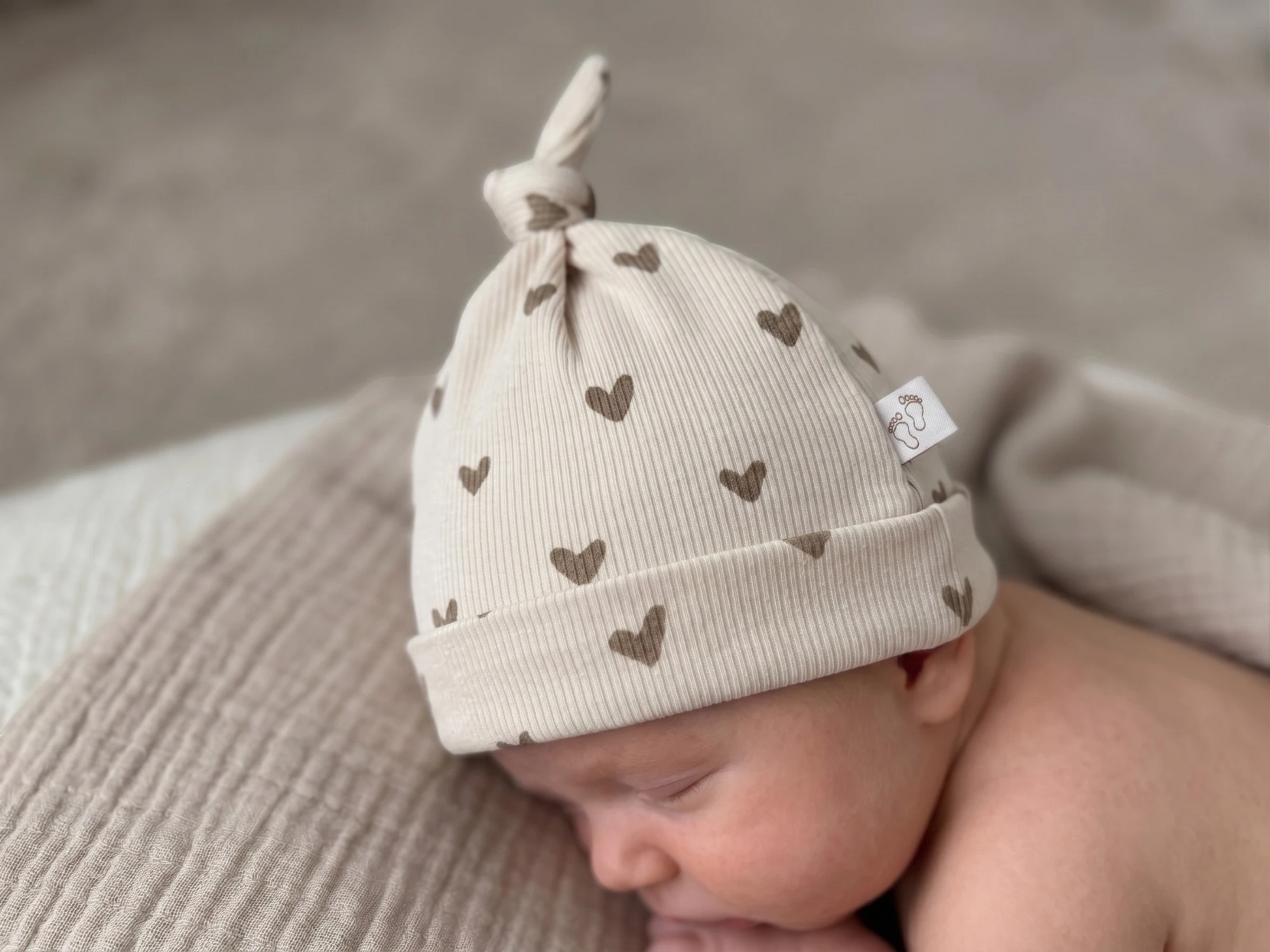 Verstelbaar knoopmutsje voor baby met grote hartjes beige
