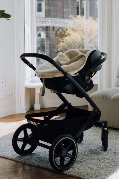 Baby in Maxi-Cosi met merino wollen voetenzak voor een comfortabele autorit.