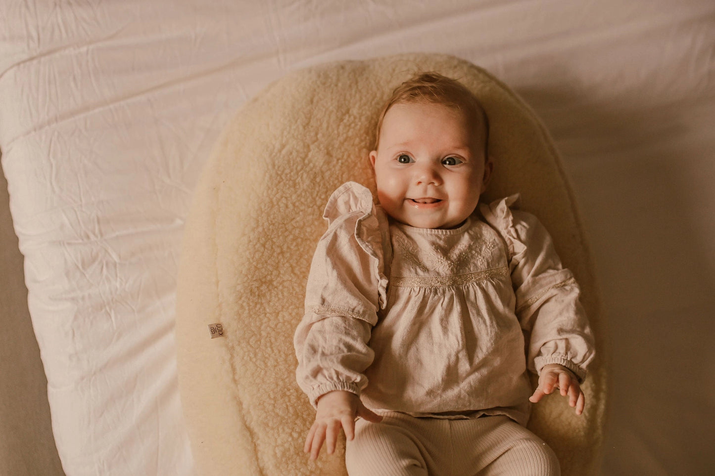 Baby ligt comfortabel op een voedingskussen met merino wollen voedingskussenhoes