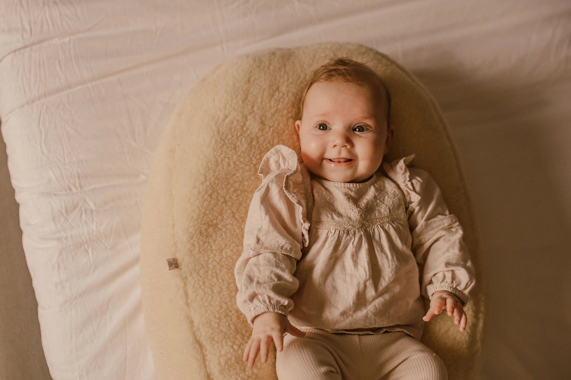 Baby ligt comfortabel op een voedingskussen met merino wollen voedingskussenhoes